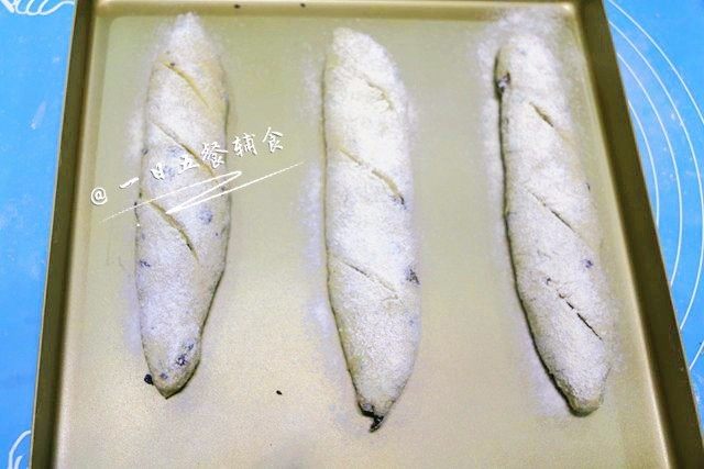 法棍 宝宝辅食,即发干酵母+ 果干+香料,面团表面撒粉,随后用蘸水的锋利刀片,沿着面团纵轴,和面团表面呈45度角干脆利落地切出刀口,两条或三条看个人喜好。注意刀口和纵轴的角度要尽量小