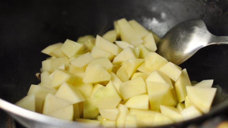 金针菇土豆粉条烩菜,4、将土豆入锅翻炒