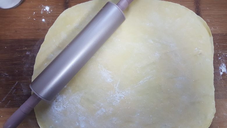 蛋黄沙琪玛,6.借助擀面杖,将面饼擀成薄的面片。