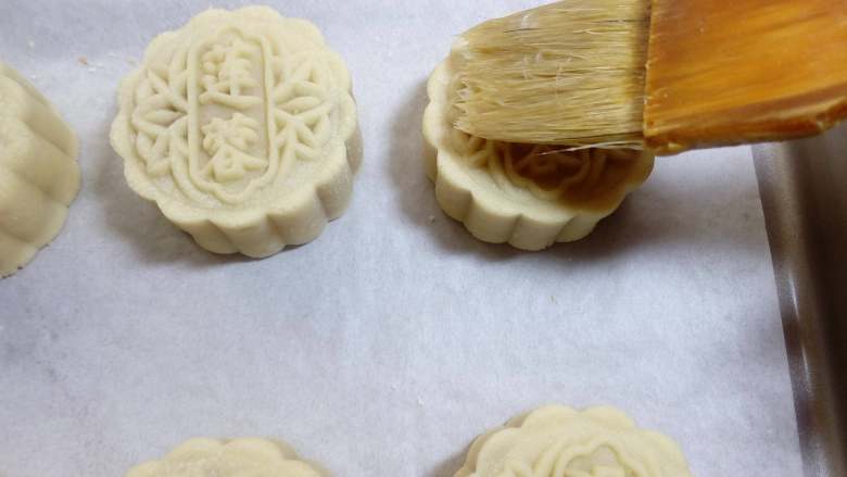 广式月饼~莲蓉蛋黄月饼,烤5分钟后的取出刷蛋液,在刷蛋液的同时,烤箱不要关掉,保持烤月饼的温度。只需要刷一层薄蛋黄水就行,软毛刷在碗边逼去多余蛋液,只在凸起的花纹上轻刷一层即可,蛋液刷得过多,会让花纹不够清晰。然后再入烤箱烤15分钟左右
各家烤箱脾气各不同,给的温度仅供参考。
在烘烤中温度过高或者面团偏干,容易引起开裂,不过小的开裂会在回油后不明显。烘烤时的温度如果偏低,会引起鼓腰、泄脚或不熟等。