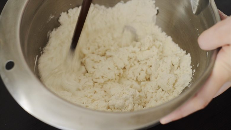 大闸蟹小笼包,200g面粉放进盆子里,准备100g水,一边倒水,一边用筷子搅拌,直到面团结块,基本上用90g左右的水就可以了。接着用手把面揉成一个团,粗糙一点没有关系,用保鲜膜包上,防止变干。