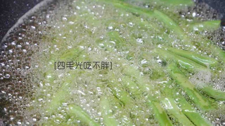 干煸四季豆,起锅烧热油,以高火高温将四季豆炸制表皮起皱捞出;