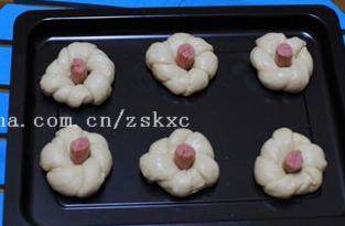 香葱花形面包,将脆皮肠放在面团中间的洞里;这个烤盘是不沾的,不用铺烤盘纸,直接将面团放在盘中即可