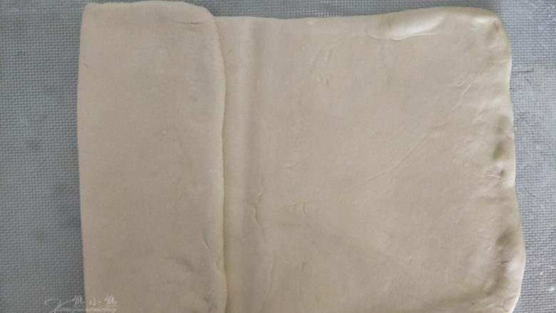 吃掉一朵花——玫瑰苹果挞,擀好后,用擀面杖在长方形的中间按一下,将面片的一端向中心折过来。
