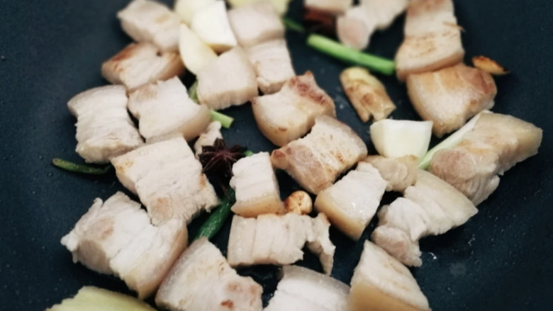 鹌鹑蛋红烧肉,葱姜放进锅中爆香,然后倒入五花肉炒香至五花肉上色。