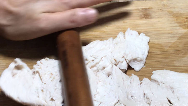 口水鸡丝,捞出浸泡的鸡胸肉,用擀面杖轻轻擀压散开