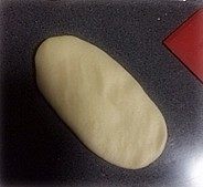 心心相映椰蓉包,取一份包好椰蓉的面团,擀开成椭圆形