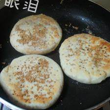 大烧饼夹肘子肉,放入锅中后,盖上锅盖,中小火开始。看到烧饼发起来了(如图),再在表面抹一层油。翻面继续,煎至两面金黄色即可。