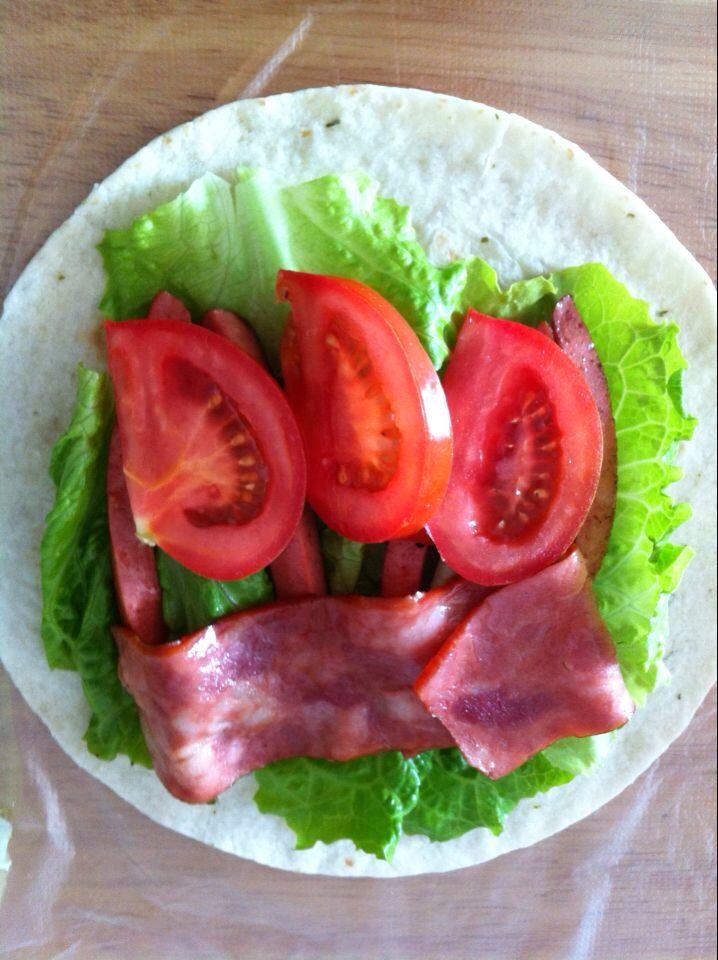 肠子培根蔬菜卷,如图，把材料放在薄饼皮上，然后卷成条状。