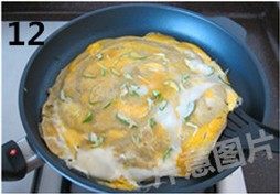 自制煎饼果子,鸡蛋上撒上适量葱花,待鸡蛋基本凝固时,用锅铲轻轻转动面饼离开锅底,并小心翻面。