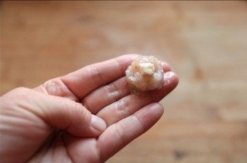 奶酪虾球,用手把虾肉团成丸子,把奶酪粒放到丸子中间包起来。