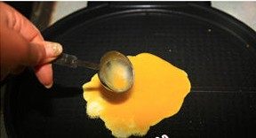 翡翠黄金培根卷,把鸡蛋打散，用勺子舀蛋液，倒入抹油的电饼铛里