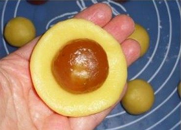 杏仁蜜桃酥,取一块酥皮面团,用手压扁,放上一块馅料