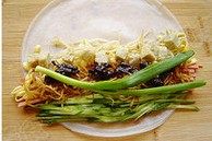 凉皮蔬菜卷,放入萝卜丝咸菜铺匀,再放入炸肉酱和小葱