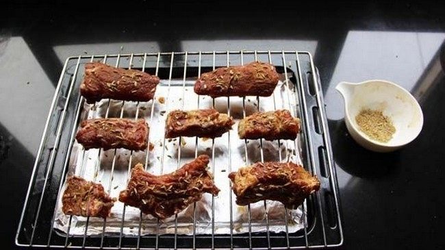 茴香排骨,烤网叠在烤盘上,烤盘里垫好锡纸,排骨放在烤网上,将排骨的两面都撒上孜然粉和茴香