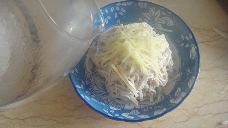 烫干丝,开水淋在姜丝上,让姜丝渗透进干丝中,倒掉后再烫,反复3次