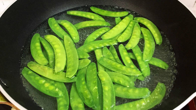 肉片炒荷兰豆,锅中烧开水后加入适量的食用油和盐,再放入荷兰豆焯水半分钟