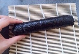 三文鱼寿司 ,完全卷起好,两手握住卷帘将寿司卷压实,卷好的寿司静置一会儿