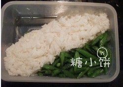 红烧猪排饭,煮熟的米饭排入饭盒中，一个角落填上炒好的豆角