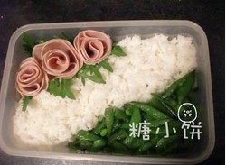 红烧猪排饭,另一角放洗净的芝麻叶，再用火腿片卷几朵花摆在上面