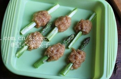芦笋鸡肉棒,取适量鸡肉糜包在芦笋棒中段，放在烤盘上。