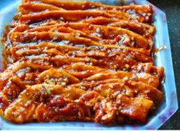 韩式烤辣酱五花肉,将肉片一片一片抹上调味料,码在大盘里,并将剩余的调味料抹在表面,腌制30分钟以上