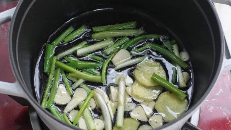 红烧羊肉煲,锅中倒入食用油烧热,下葱段、姜片和蒜片小火炒出香味儿。