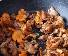 虾球溜肉片,锅中留少许底油,将蒜片放入锅中爆香,放入炸好的虾球、肉片和胡萝卜大火翻炒;
