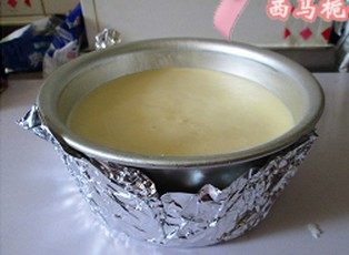 榴莲芝士蛋糕,将榴莲芝士糊倒入有饼干底的模具中。蛋糕圆模外面包上锡纸