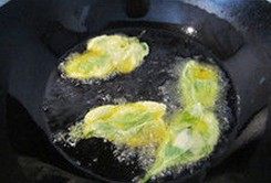 香炸薄荷,将炒锅放油烧到6成热,提起沾满面糊的薄荷在盆边上刮2下,刮去多余的面糊,放入油锅炸