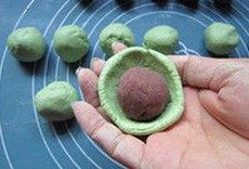 艾草青团,取一个面团用水捏成窝状,放上一个豆沙馅,滚圆