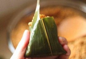 鲜肉棕,将粽叶由下往上翻折盖住糯米,同时侧面的粽叶翻折于内避免漏米