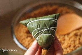 鲜肉棕,逆时针旋转90度,将粽叶弯出尖角,用绳子捆绑住即可