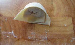 乌鸡大馄饨,每片馄炖皮中靠近短边的一边包入适量馅料，并卷起来，两头捏紧一个皮薄馅大的大馄饨包好了