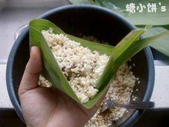 板栗排骨粽,用糯米将馅料覆盖住，前段捏尖，尾端向上翻折