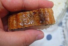 鳗鱼寿司,用手取一小块米饭,放在左手上,将鳗鱼条放在攥好的米饭上