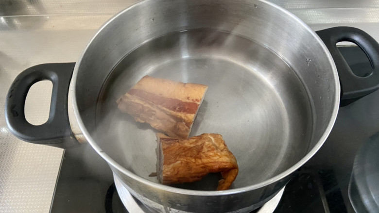 腊肉炒冬笋➕外婆菜腊肉炒冬笋,锅中重新加水,放入洗干净的腊肉,煮开后加盖小火炖煮15分钟,除去多余盐分,也可以使腊肉柔软,吃起来口感不会很硬