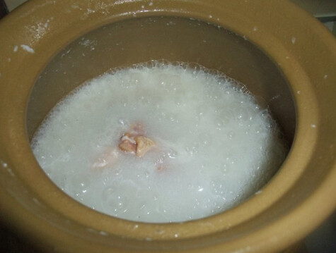 鲜鲍鱼鸡粥,转大火后下鸡块和姜丝,顺着一个方向搅拌,直至鸡块煮熟即可关火,关火后撒上葱粒即可