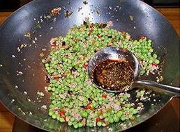小炒豌豆,下滑散的肉泥和大蒜末，下蒸鱼豉油和陈醋，翻炒均匀，淋麻油，炒匀出锅即可
