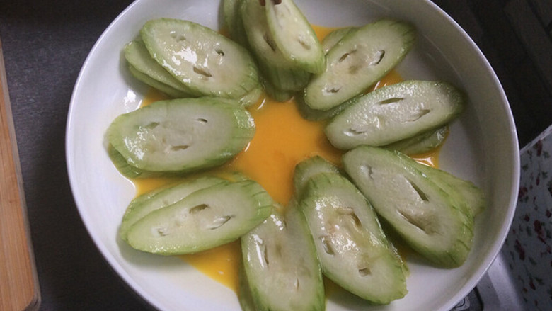 蒜蓉丝瓜蒸蛋,一个鸡蛋打散铺在碗底,把丝瓜2片一起铺在蛋液上,铺满