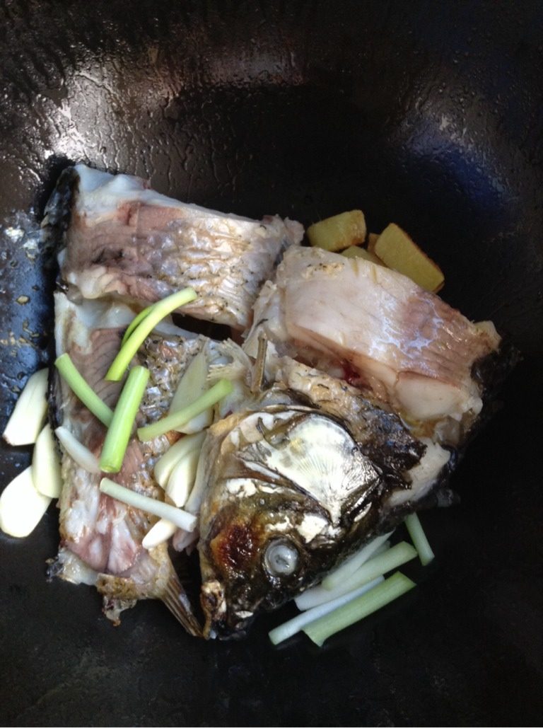 酱炖鲤鱼,2分钟后轻轻把鱼翻另一面,加葱段,蒜瓣,煎俩分钟