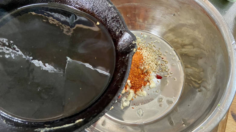 凉拌蒜蓉西兰花,取一耐热的盆,加入一汤匙辣椒粉,一汤匙熟白芝麻,蒜末小米辣,油烧到8成热,分次浇在辣椒粉上,激发香味,拌匀