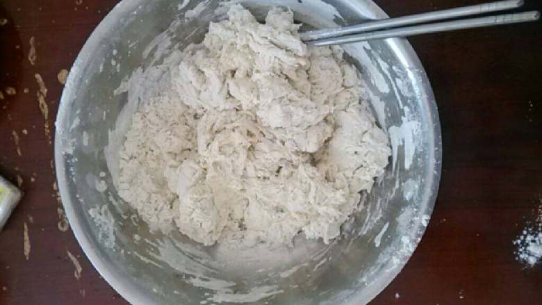 手工拉面,将温水缓缓倒入面粉中,边到边搅拌至面粉呈棉絮状