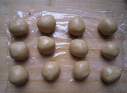 广式豆沙月饼,筛入低筋面粉,混合成面团,包上保鲜膜醒一小时后分成20g一个小球