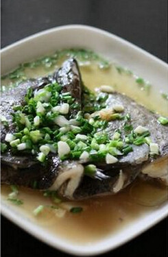 葱油鸦片鱼头,取出鱼头撒上葱花，另起油锅，将油烧热，并浇于鱼头上，葱油香四溢