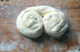 葱油手抓饼,将面片从上往下卷起来,从左右两端将面条卷起来,形成两个圈;