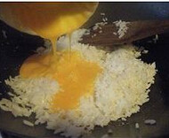 鲍汁海鲜炒饭,炒锅里放油。烧热后加入冷饭,炒散后,加入蛋黄,翻炒均匀