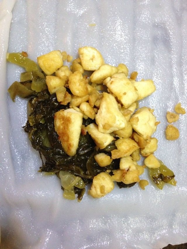 客家肠粉,摊开蒸热的肠粉皮,放豆腐和咸菜各一勺,像卷春卷一样卷起来