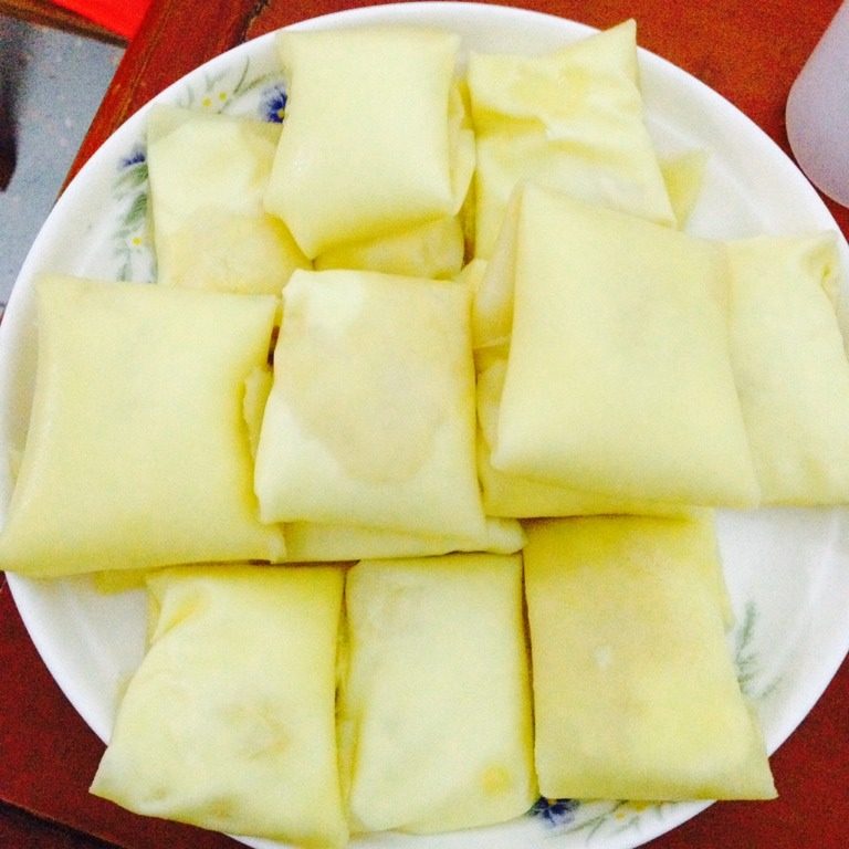 最新榴莲班戟,平铺蛋皮 加入榴莲肉 再挤上奶油 再包好 放在速冻半小时 取出对切 再放入冷藏保冷