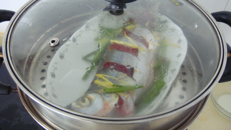 清蒸白水鱼,之后锅内烧水水烧开后放入鱼大火8分钟后熄火加盖焖2分钟端出,去掉鱼背上葱断,加入切成细丝的青椒和鲜酱油